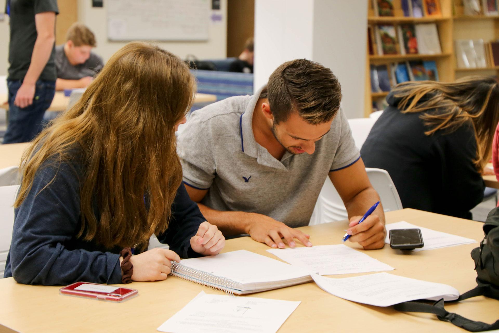 a peer tutor tutoring a classmate in the tutoring center